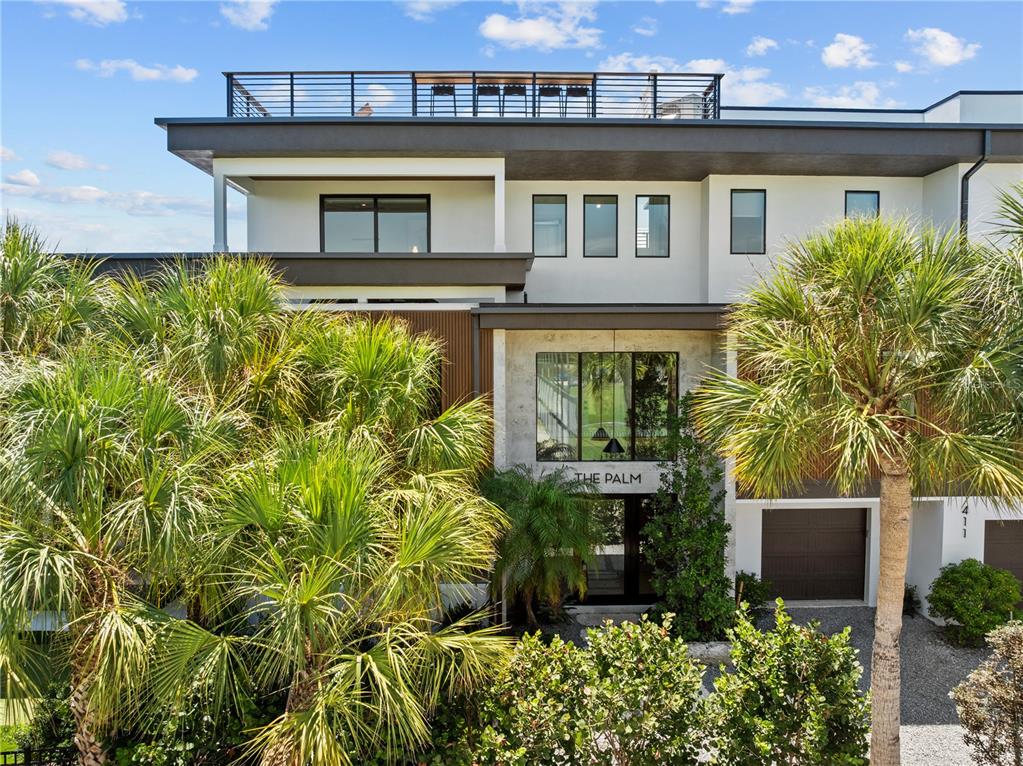 A modern multi-story building with a rooftop deck, palm trees, and a glass-paneled entrance — 411 PALM AVENUE, ANNA MARIA, FL
