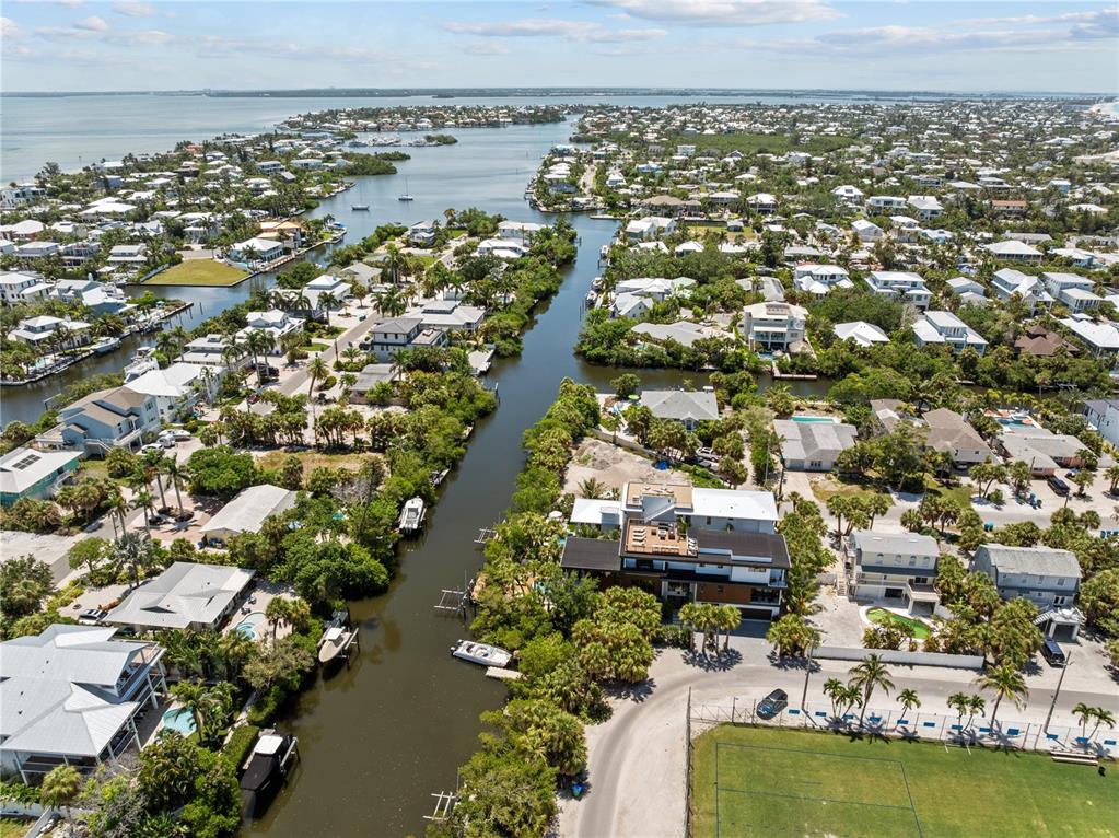 An aerial view shows waterfront homes along a canal leading to a large bay — 411 PALM AVENUE, ANNA MARIA, FL