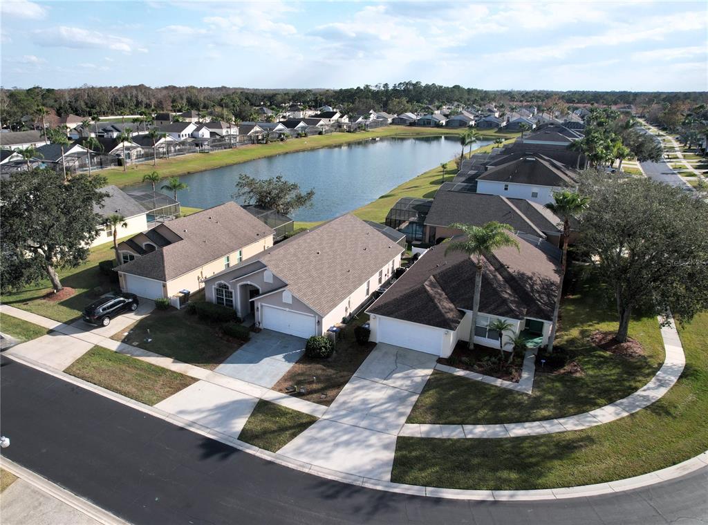 An aerial view shows suburban houses with driveways situated along a pond in a neighborhood — 1068 LAKE BERKLEY DRIVE, KISSIMMEE, FL