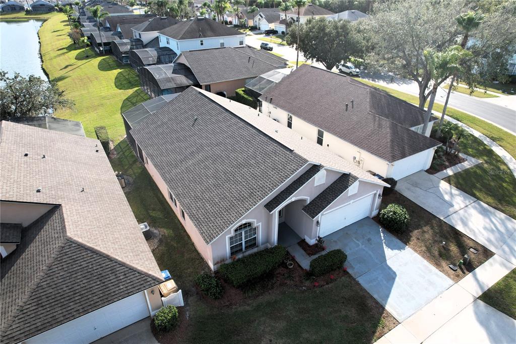 An aerial view shows a suburban house with a shingled roof and a driveway — 1068 LAKE BERKLEY DRIVE, KISSIMMEE, FL