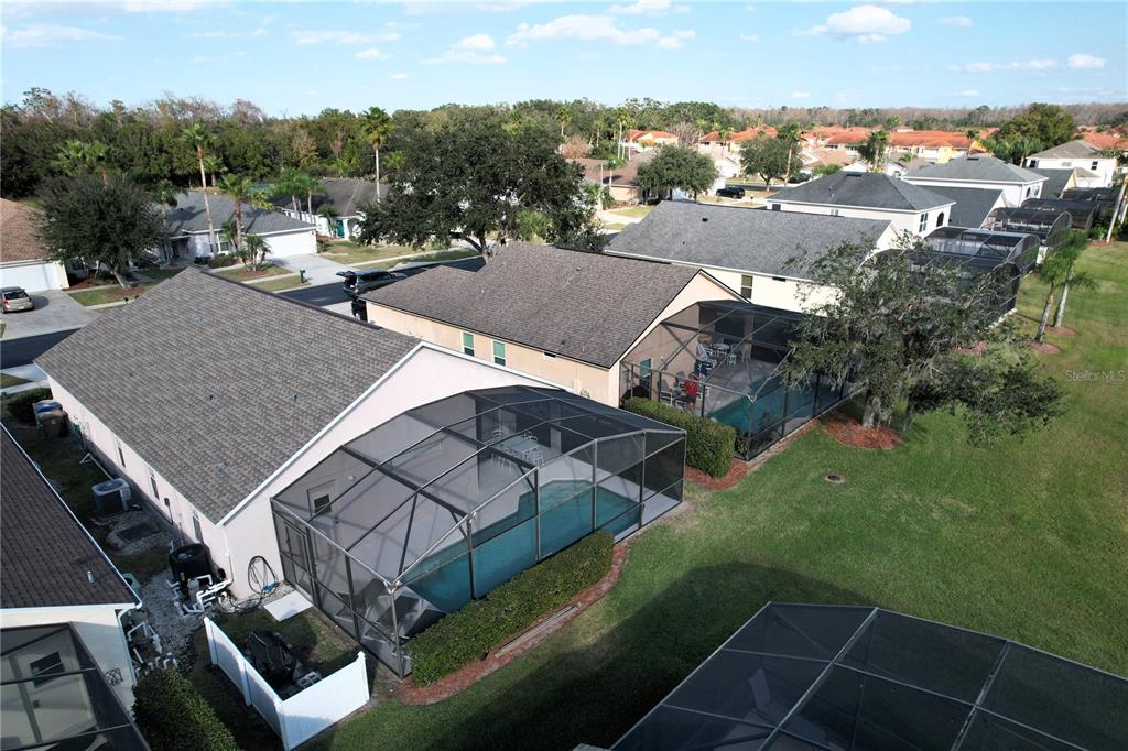 An aerial view shows suburban houses with screened-in swimming pools and backyard lawns — 1068 LAKE BERKLEY DRIVE, KISSIMMEE, FL