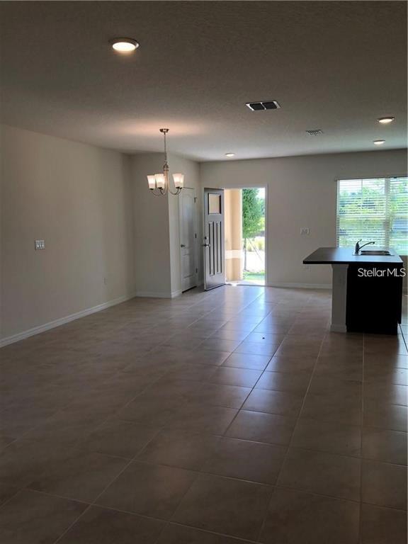 An open-concept room features light-colored tile flooring, a dining chandelier, and a kitchen island — 1851 RED CANYON DRIVE, KISSIMMEE, FL