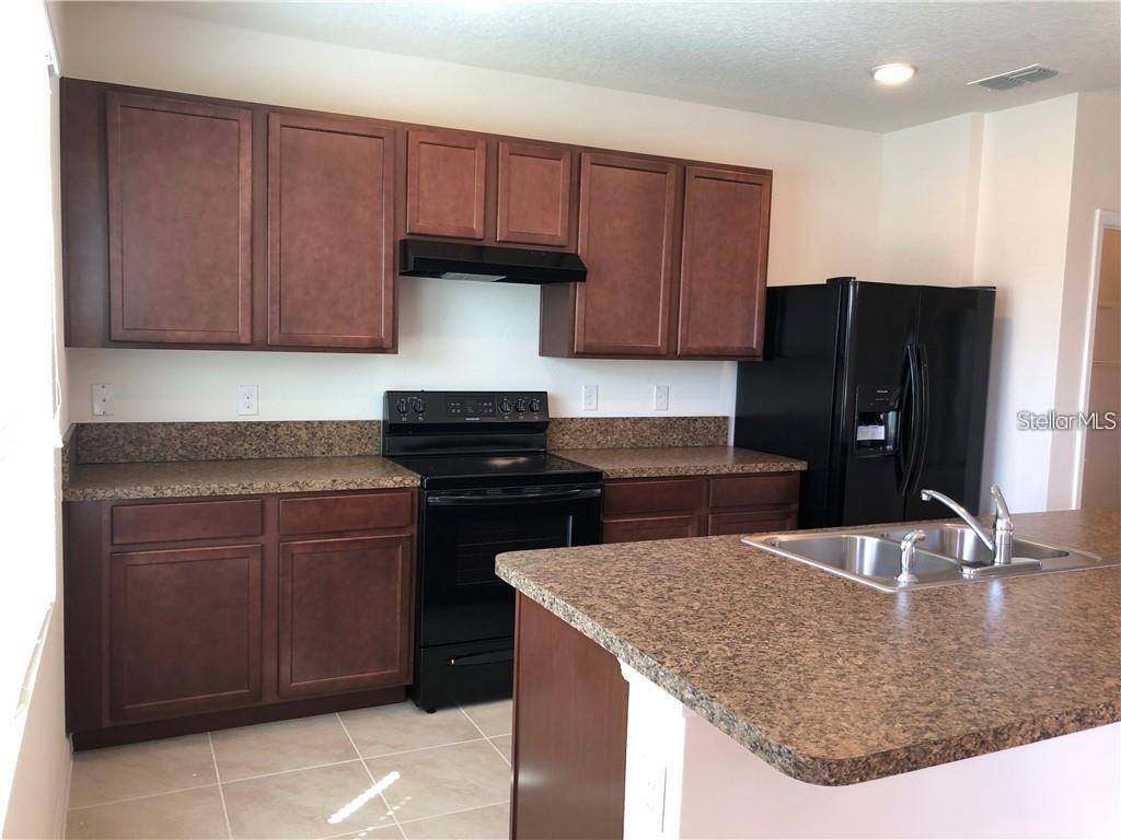 A kitchen features dark wood cabinets, brown laminate countertops, and black appliances — 1851 RED CANYON DRIVE, KISSIMMEE, FL