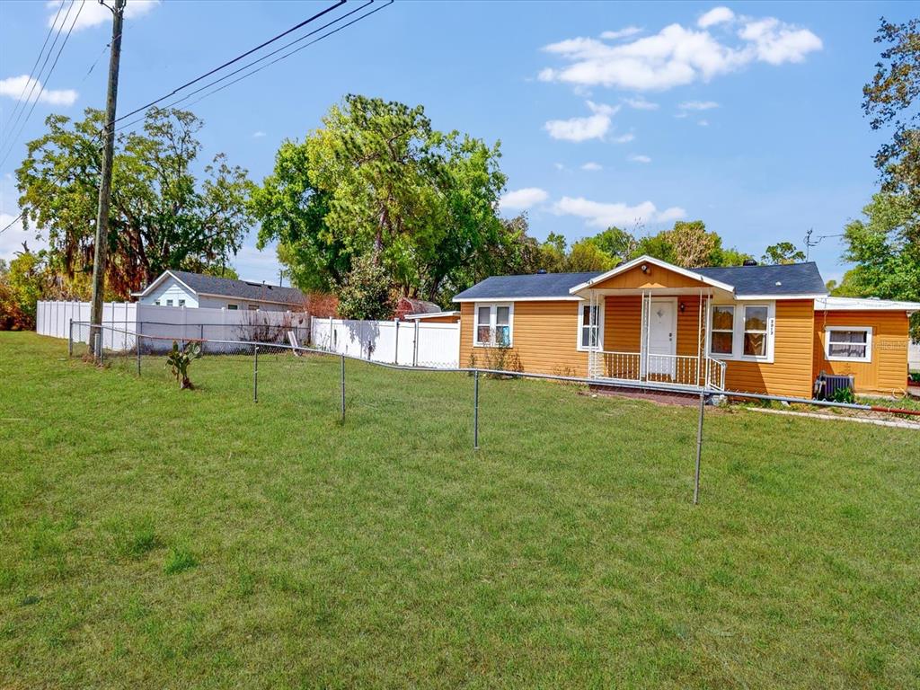 A yellow single-story house with a white porch sits behind a chain-link fence — 2017 MILLER BOULEVARD, FRUITLAND PARK, FL
