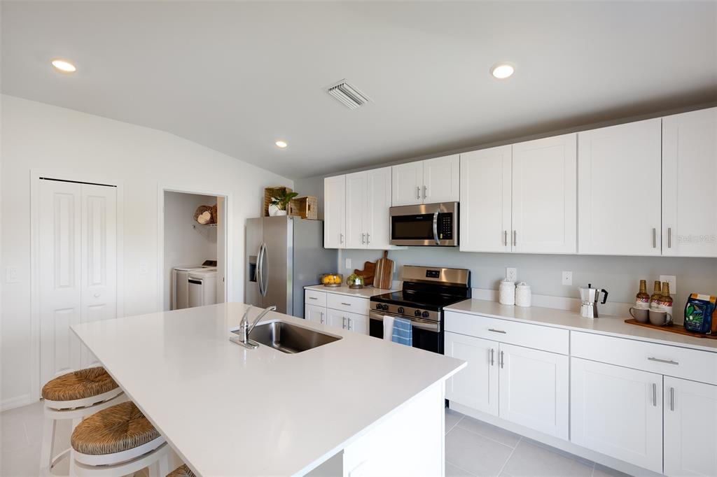 A modern kitchen features white cabinetry, stainless steel appliances, and a large central island — 3524 IMARI STREET, NORTH PORT, FL