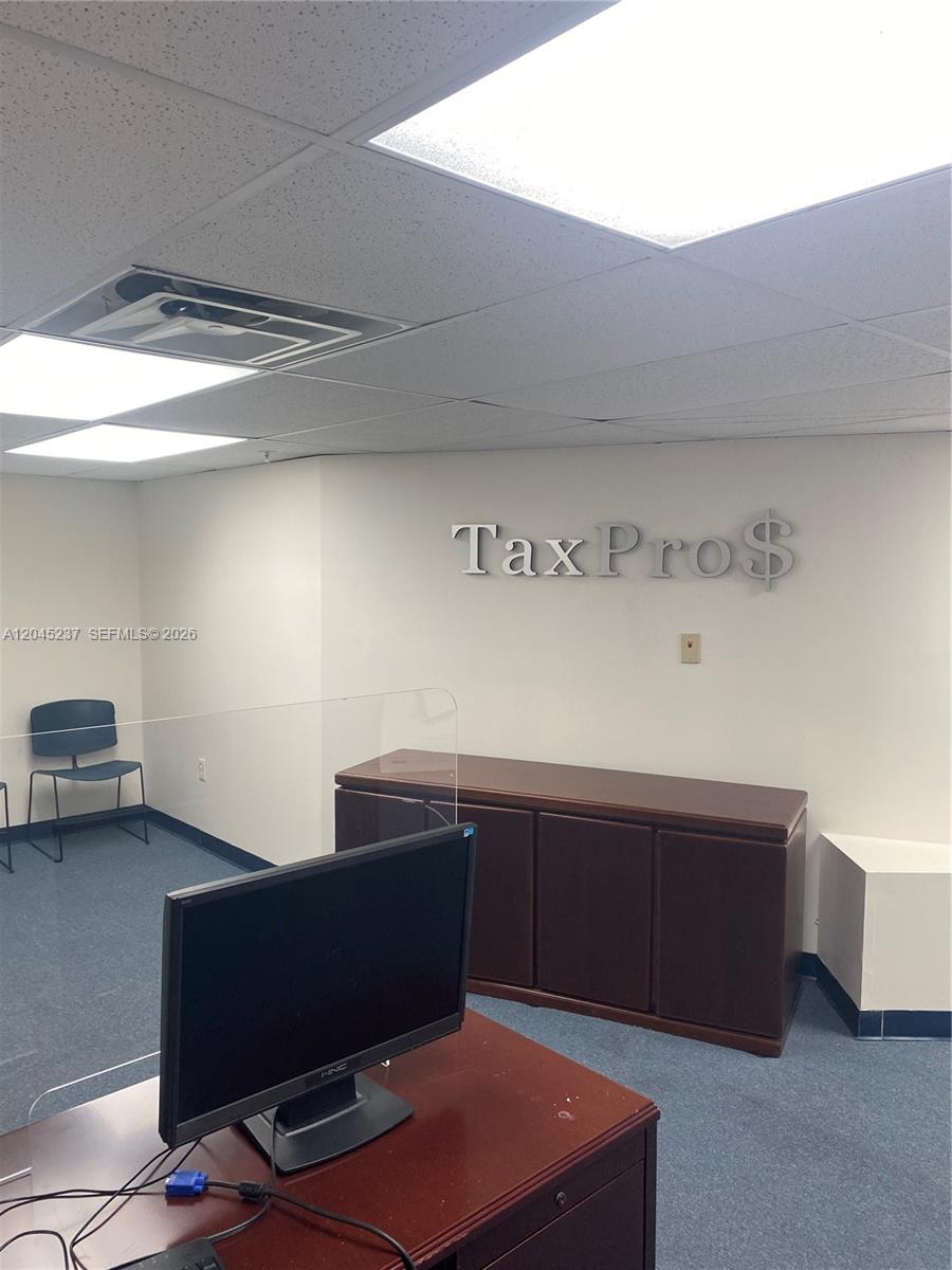 An office reception area features a desk, a computer monitor, and a TaxPro$ wall sign — 1201 SW 8th St, Miami FL 33135, MIAMI, FL