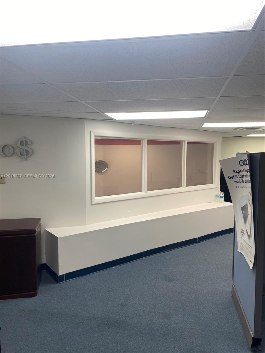 An interior view shows a carpeted room with a white wall, a window, and ceiling lights — 1201 SW 8th St, Miami FL 33135, MIAMI, FL