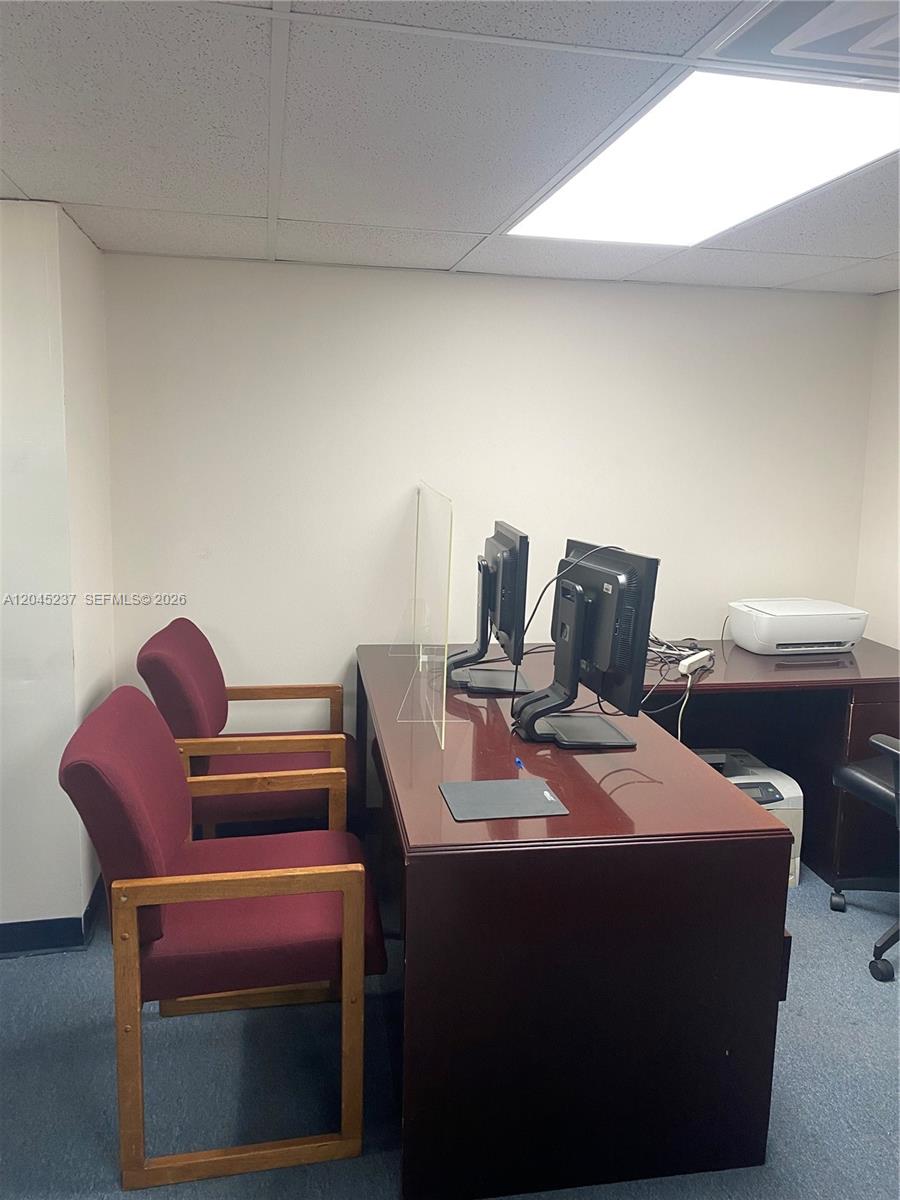 An office space features a dark wood desk, two burgundy chairs, and computer equipment — 1201 SW 8th St, Miami FL 33135, MIAMI, FL