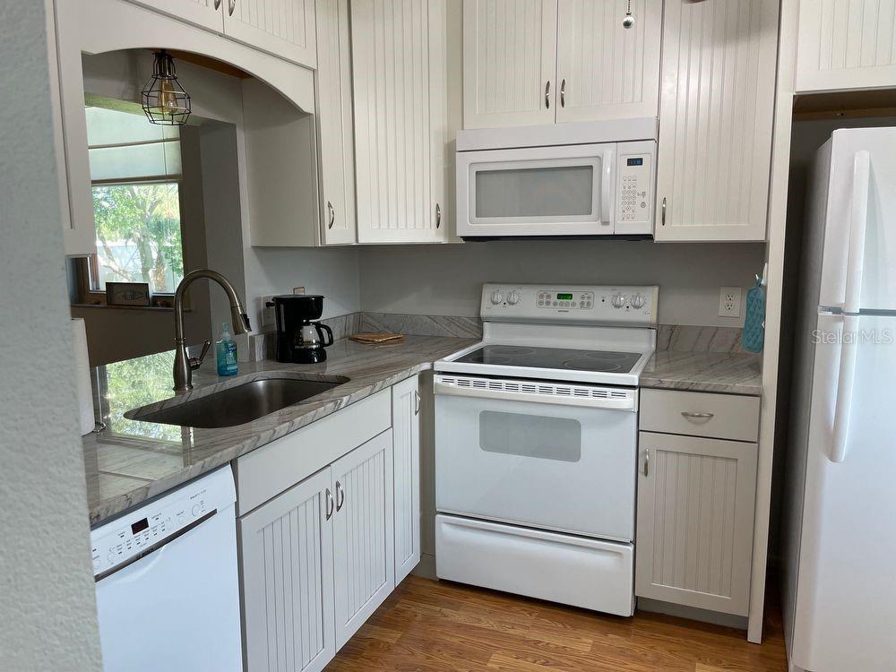 A kitchen features white cabinetry, a white stove, a dishwasher, and stone-look countertops — 206 LAKEWOOD DRIVE UNIT 206, BRADENTON, FL