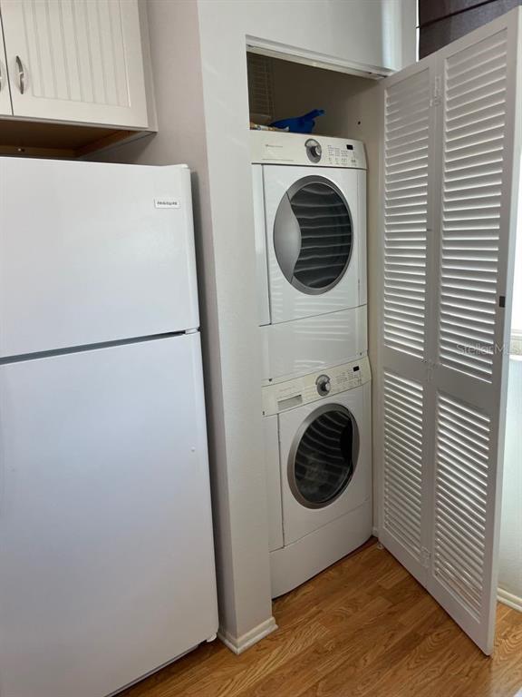 A white refrigerator stands next to a stacked washer and dryer in a small closet — 206 LAKEWOOD DRIVE UNIT 206, BRADENTON, FL