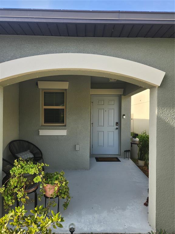 A covered front porch features a light blue door, a window, and potted plants — 16725 DELIA STREET, WIMAUMA, FL