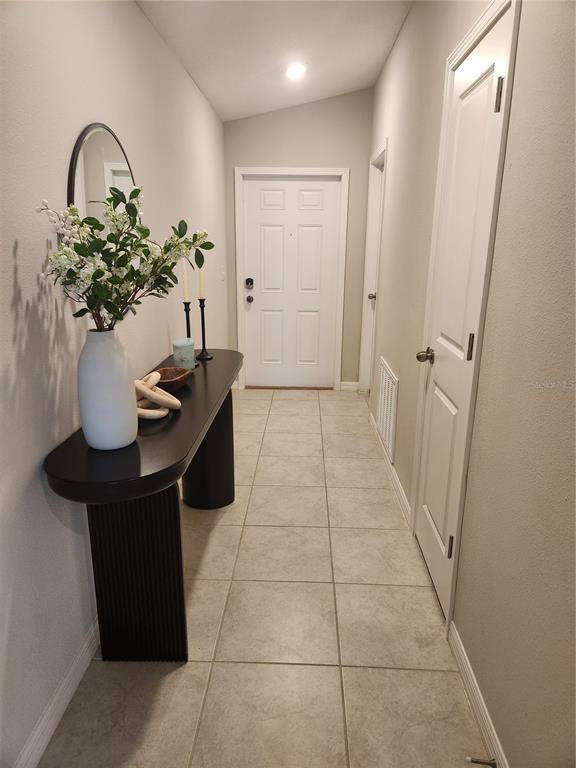 A tiled entryway features a black console table with a vase and a white door — 16725 DELIA STREET, WIMAUMA, FL
