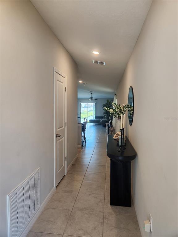 A tiled hallway leads from an entryway past a console table toward an open living area — 16725 DELIA STREET, WIMAUMA, FL