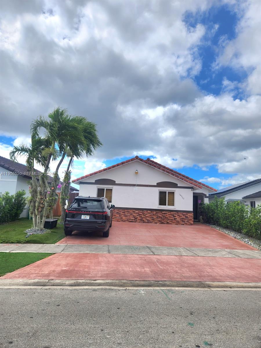 A single-story house with a red-tiled roof, stone facade, and a black SUV parked outside — 14330 SW 179th Ln, Miami FL 33177, MIAMI, FL