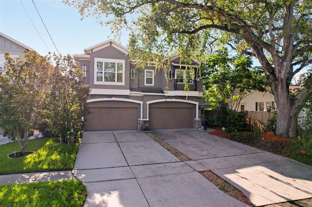 A two-story duplex with two garage doors and a concrete driveway under a large tree — 112 S BUNGALOW PARK AVENUE UNIT 1, TAMPA, FL