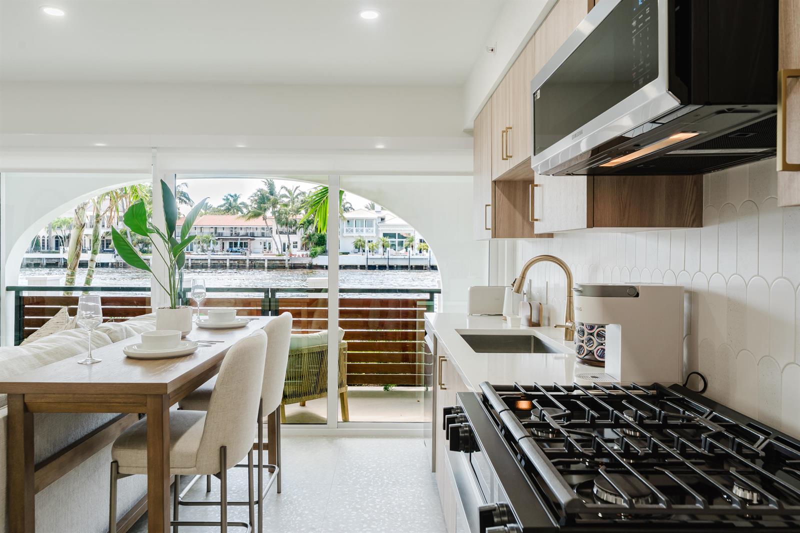 A modern kitchen with light wood cabinets, a gas stove, and a dining area overlooking water — 1075 Spanish River Road, Boca Raton FL 33432, BOCA RATON, FL