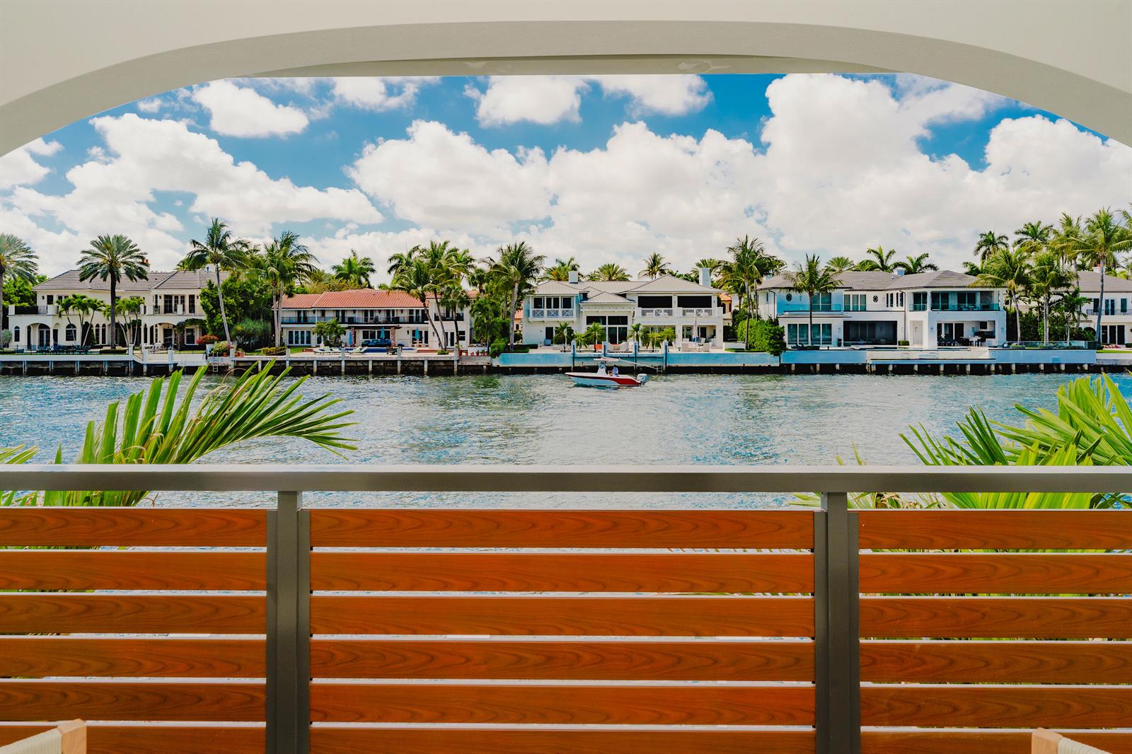 A view of a waterfront canal and luxury homes from a balcony with wooden railings — 1075 Spanish River Road, Boca Raton FL 33432, BOCA RATON, FL