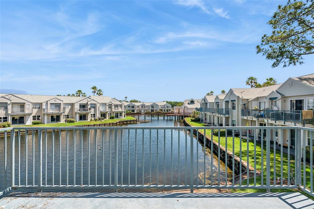 A view from a balcony overlooking a canal between two rows of residential apartment buildings — 2564 WOODGATE BOULEVARD UNIT 204, ORLANDO, FL