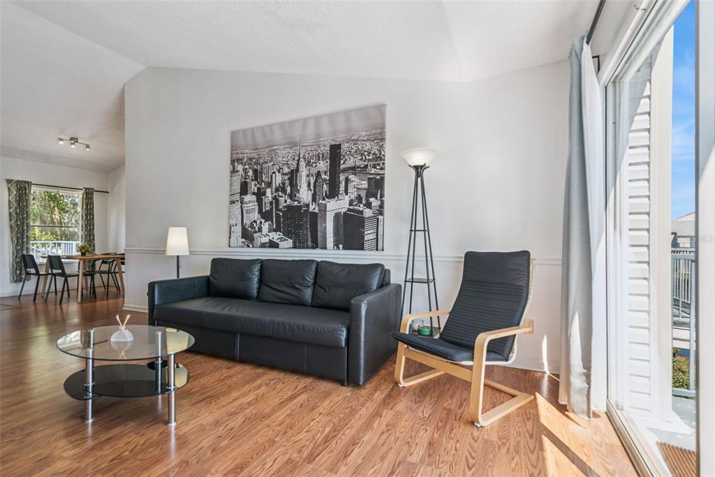 A living room features a black sofa, a glass coffee table, and a city skyline print — 2564 WOODGATE BOULEVARD UNIT 204, ORLANDO, FL