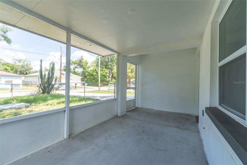 A screened-in concrete porch features white walls and a view of a fenced yard — 8115 N SEMMES STREET, TAMPA, FL