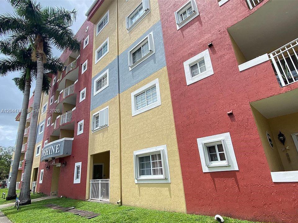 A multi-story apartment building features a colorful exterior with red and yellow stucco walls — 21 E 3rd St # 205, Hialeah FL 33010, HIALEAH, FL