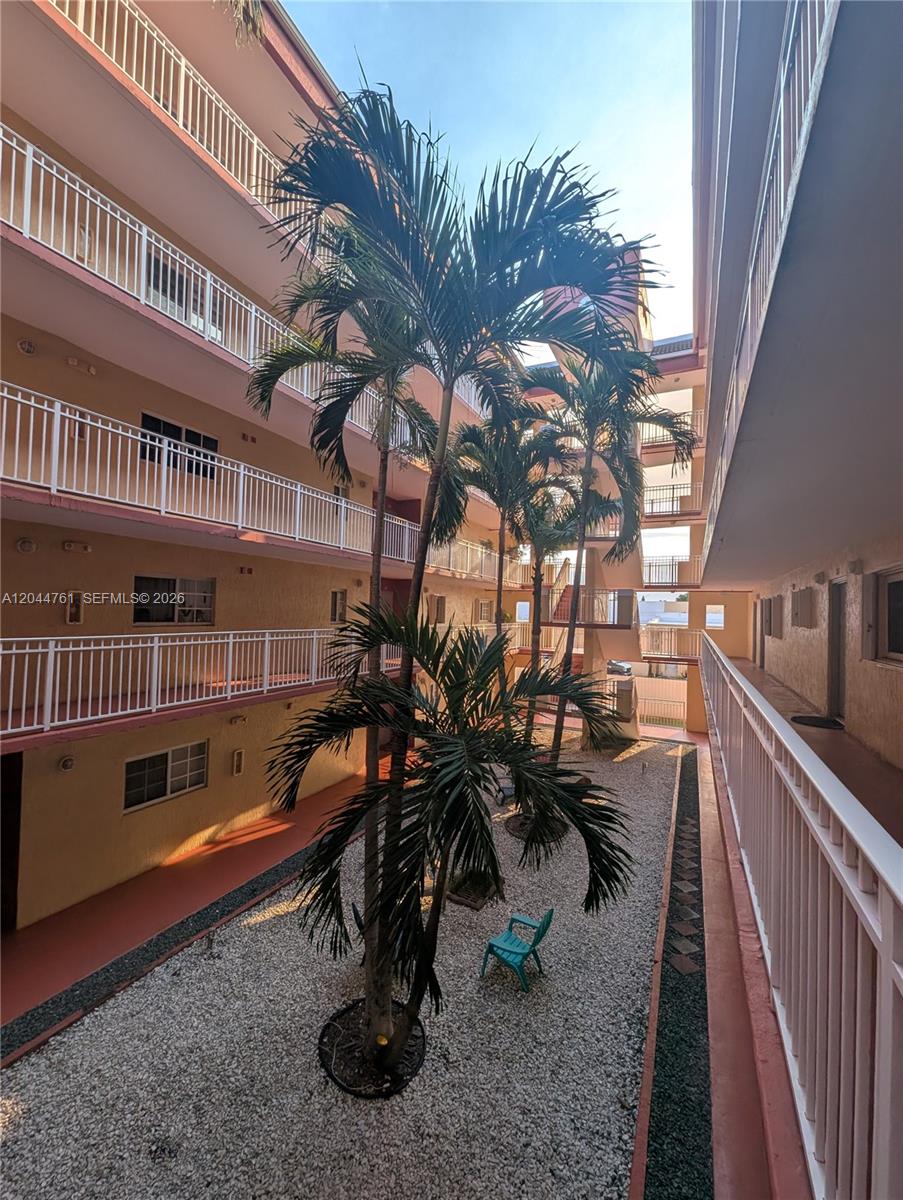 An outdoor courtyard with palm trees and gravel landscaping sits between two apartment building wings — 21 E 3rd St # 205, Hialeah FL 33010, HIALEAH, FL