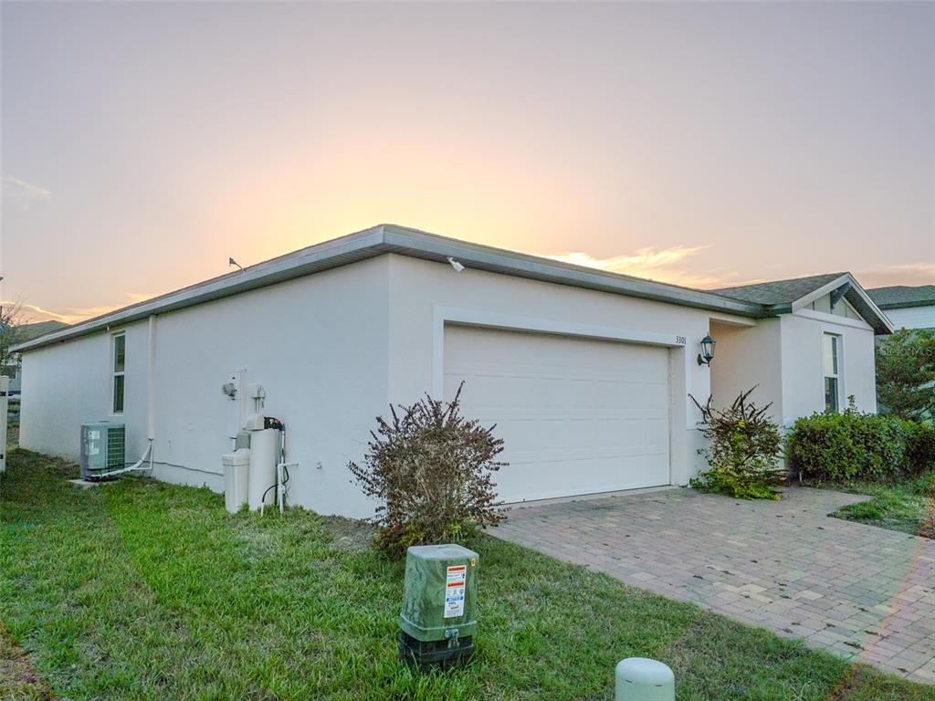 A single-story house exterior features a white stucco finish, a two-car garage, and a driveway — 3301 WEITZEL DRIVE, HAINES CITY, FL