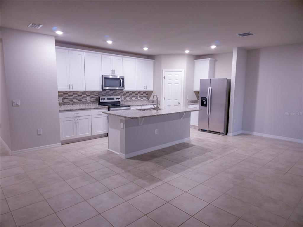 A kitchen features white cabinets, granite countertops, stainless steel appliances, and a central island — 3301 WEITZEL DRIVE, HAINES CITY, FL