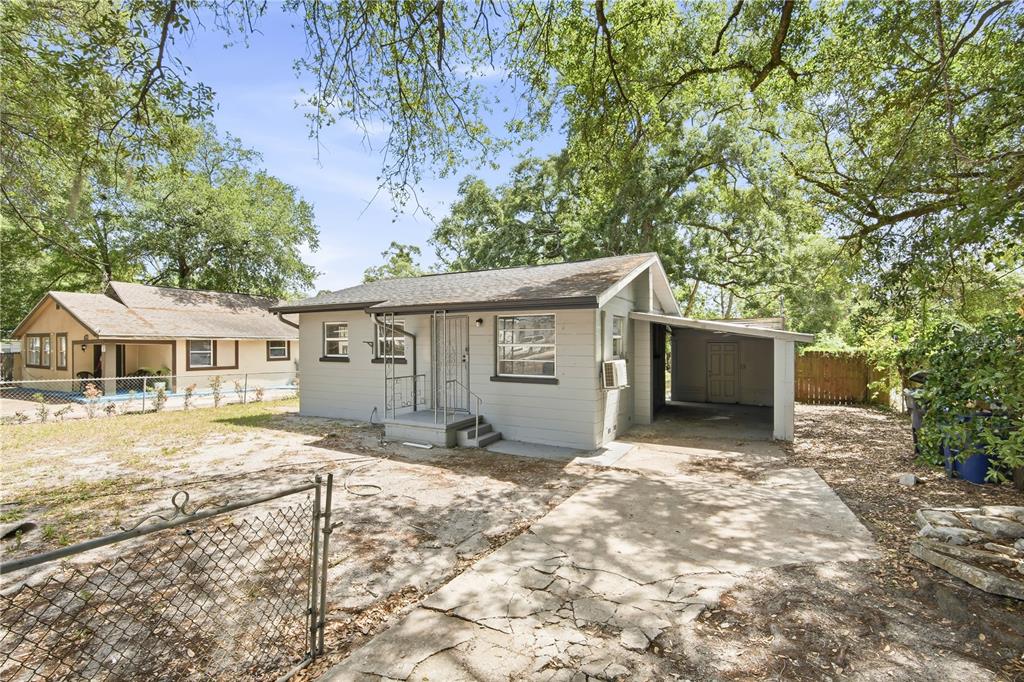 A single-story gray house with a carport, a concrete driveway, and a chain-link fence — 6209 N 43RD STREET, TAMPA, FL