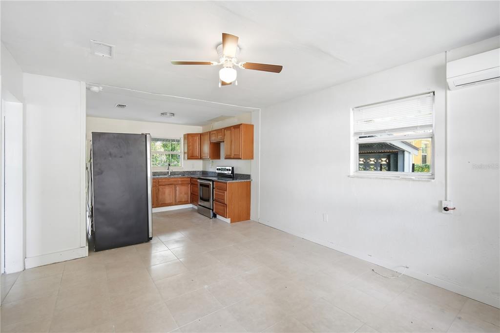 An open-concept kitchen and living area features white walls, tile flooring, and wood cabinetry — 6209 N 43RD STREET, TAMPA, FL