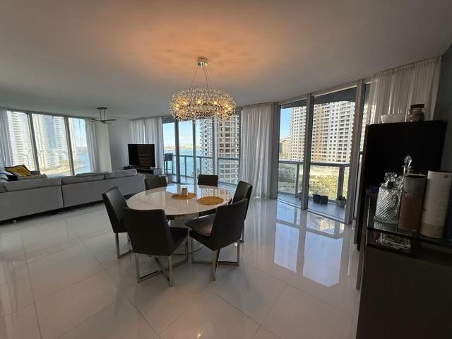 A modern dining area with a crystal chandelier, white tile floors, and floor-to-ceiling windows — 465 Brickell Avenue # 1201, Miami FL 33131, MIAMI, FL