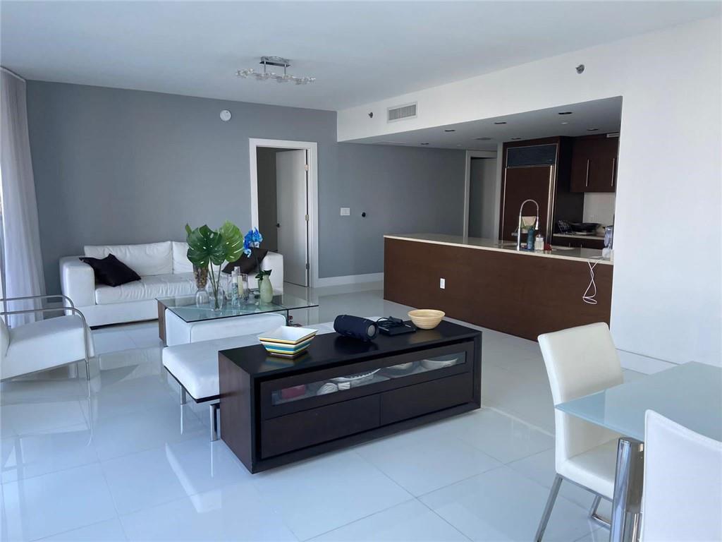 A modern living room and kitchen area with white tile floors and dark wood furniture — 465 Brickell Avenue # 1201, Miami FL 33131, MIAMI, FL