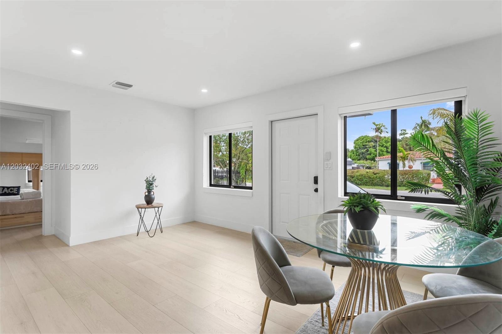 A bright dining area features light wood flooring, a glass table, and a white door — 151 NW 146th St # 151, Miami FL 33168, MIAMI, FL