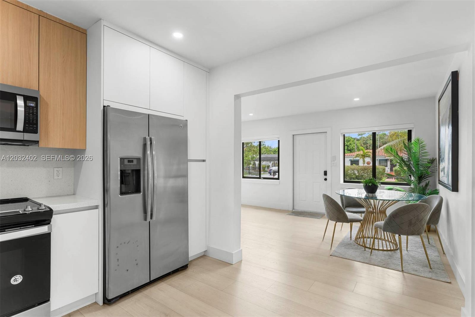 A modern kitchen with stainless steel appliances opens into a dining area with a glass table — 151 NW 146th St # 151, Miami FL 33168, MIAMI, FL