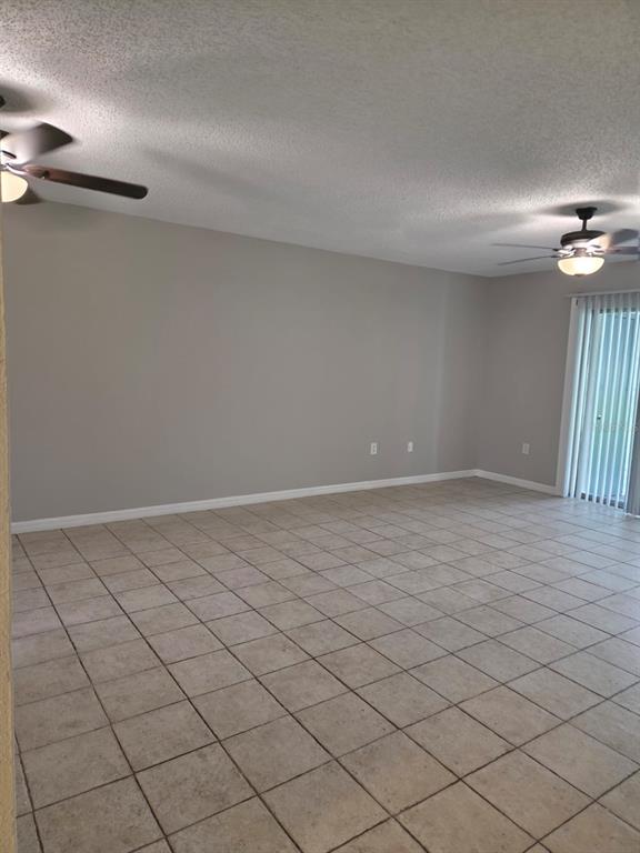 An empty room features light-colored tile flooring, gray walls, and two ceiling fans — 4203 S SEMORAN BOULEVARD UNIT 4, ORLANDO, FL