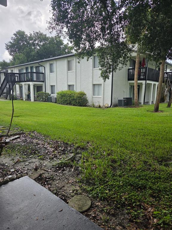 A two-story apartment building with white stucco siding, black railings, and a grassy lawn — 4203 S SEMORAN BOULEVARD UNIT 4, ORLANDO, FL