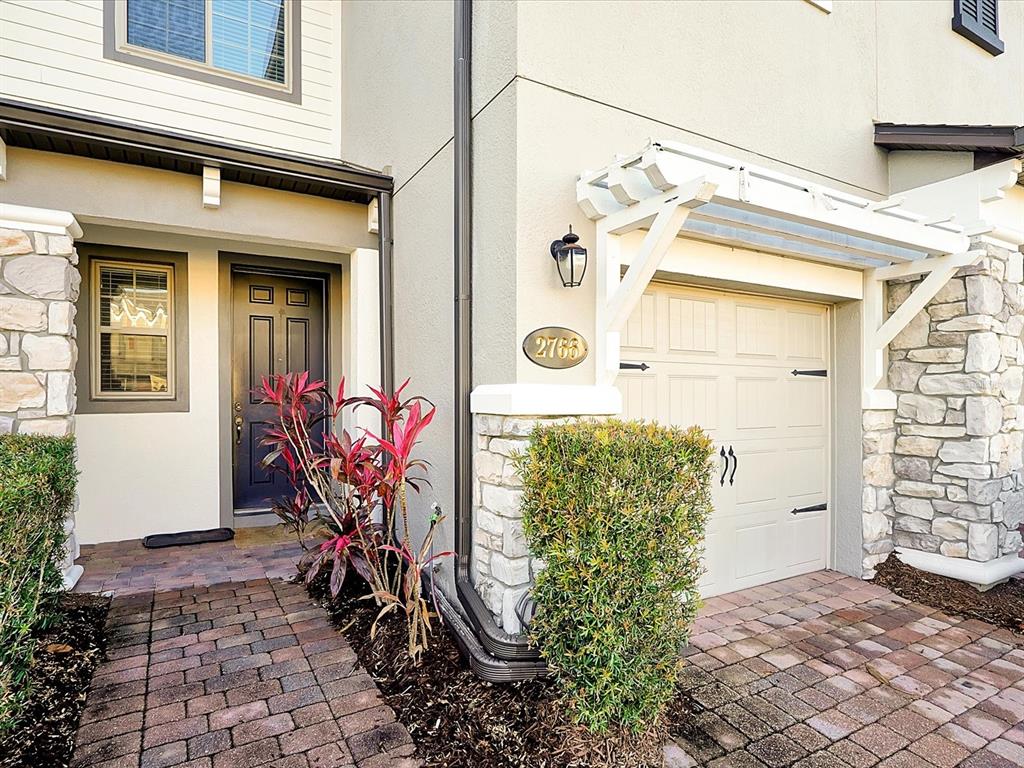 The exterior of a townhouse features a stone-accented facade, a dark front door, and a garage — 2766 WHITE ISLE LANE, ORLANDO, FL