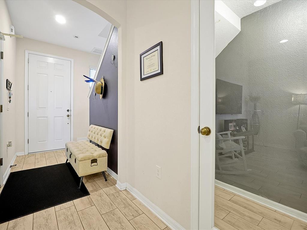 An entryway features a tufted bench, a dark accent wall, and a glass-paneled door — 2766 WHITE ISLE LANE, ORLANDO, FL