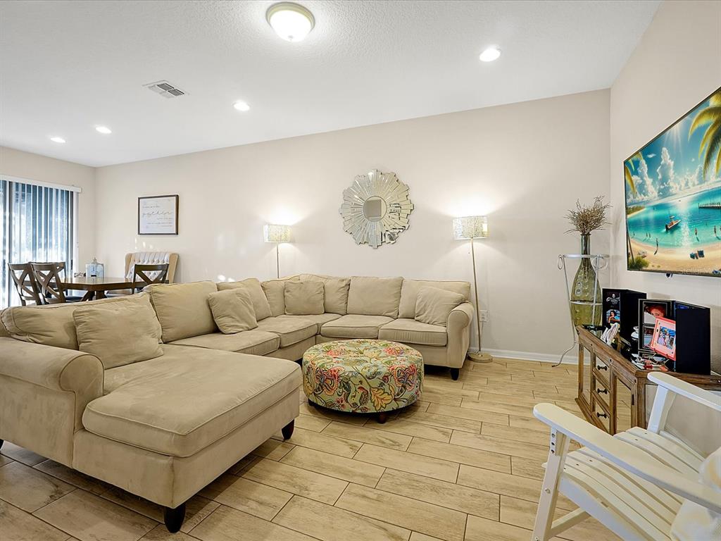 A living room features a beige sectional sofa, a floral ottoman, and light wood-look flooring — 2766 WHITE ISLE LANE, ORLANDO, FL