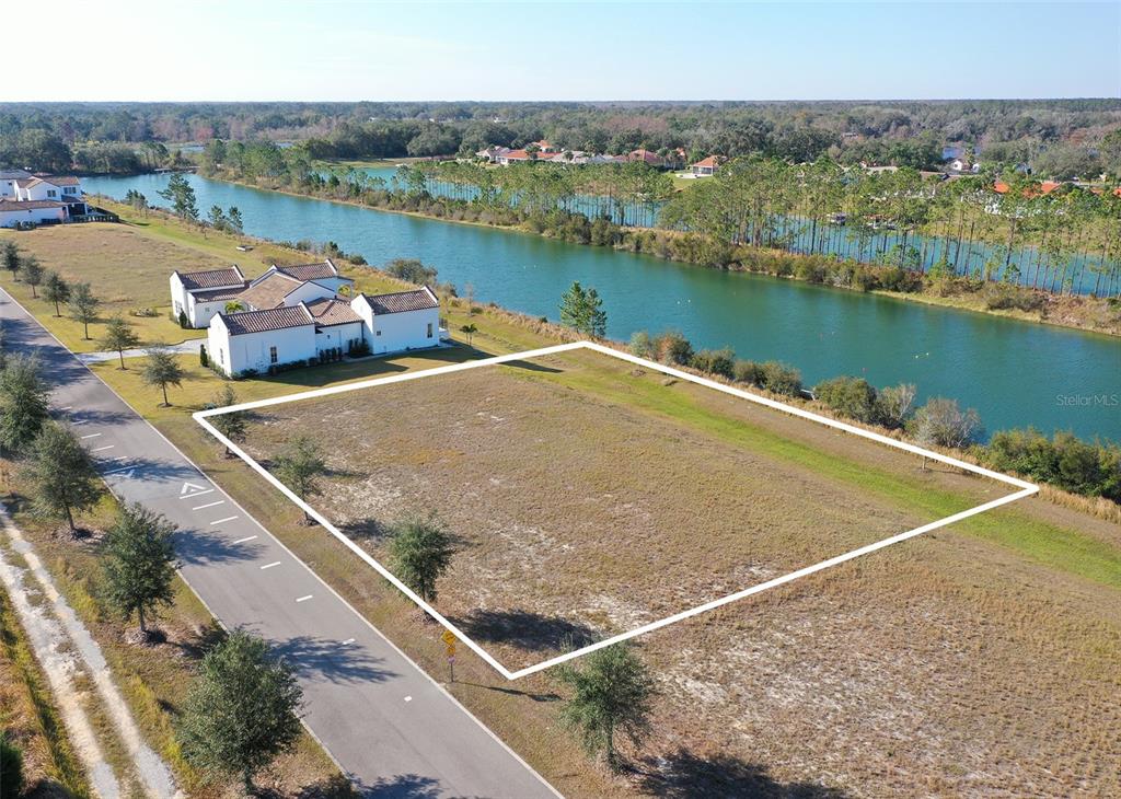 An aerial view shows a vacant rectangular lot situated next to a road and water — 13085 SWINNEY LANE, CLERMONT, FL