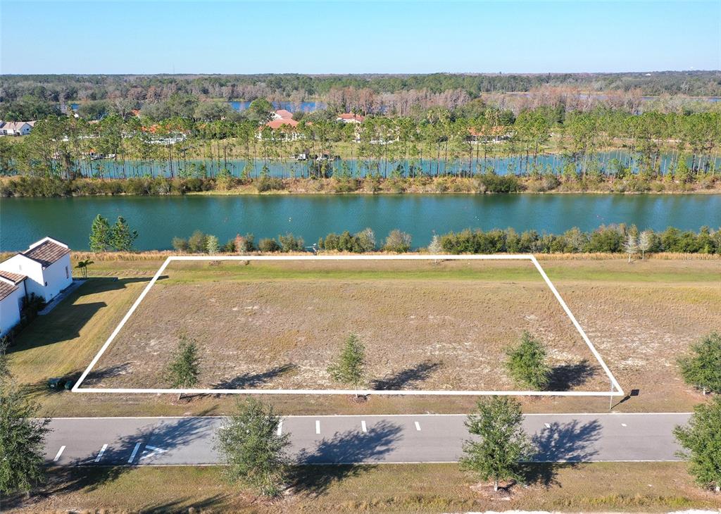 An aerial view shows a vacant rectangular lot bordered by a road and a lake — 13085 SWINNEY LANE, CLERMONT, FL