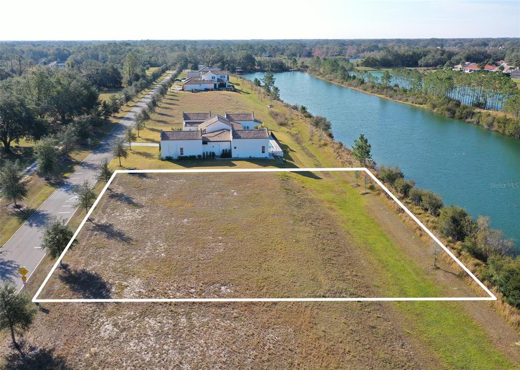 An aerial view shows a vacant rectangular lot bordered by a road and a lake — 13085 SWINNEY LANE, CLERMONT, FL