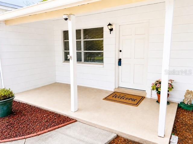 A white house exterior features a covered front porch, a white door, and a welcome mat — 10964 84TH AVENUE, SEMINOLE, FL