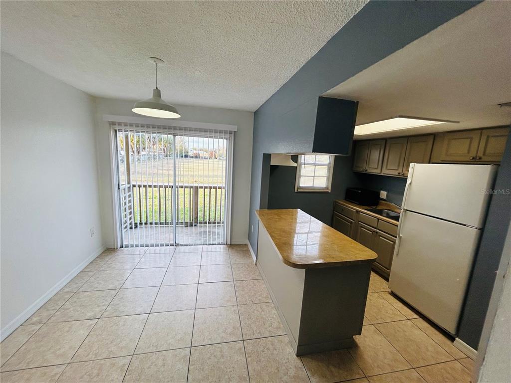 A kitchen with a breakfast bar, tile flooring, and a sliding glass door to a deck — 2775 L B MCLEOD ROAD UNIT B, ORLANDO, FL