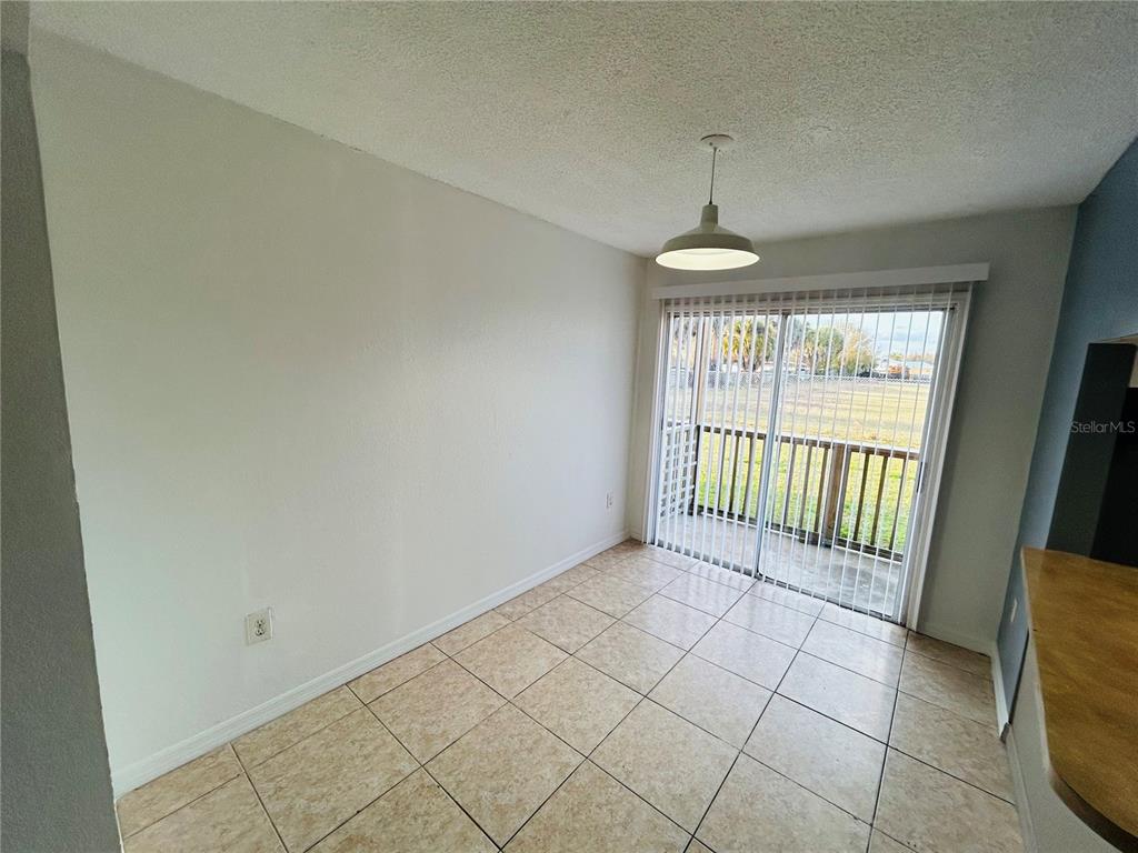 A dining area features beige tile flooring, a pendant light, and sliding glass doors to a balcony — 2775 L B MCLEOD ROAD UNIT B, ORLANDO, FL