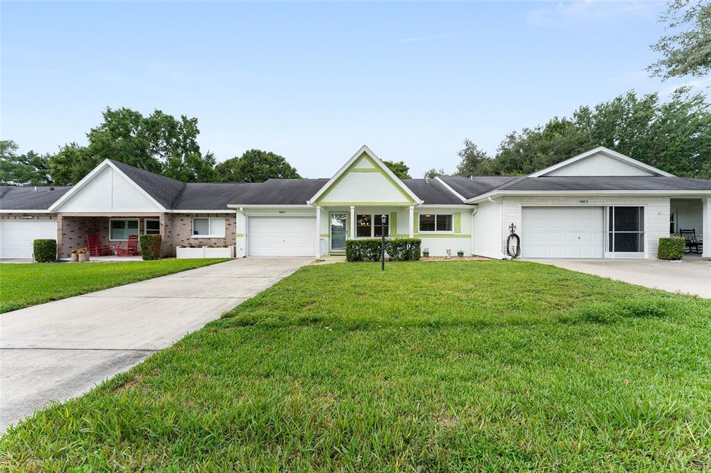 A row of single-story attached homes features white brick facades, gabled roofs, and concrete driveways — 9660 SW 92ND COURT UNIT C, OCALA, FL