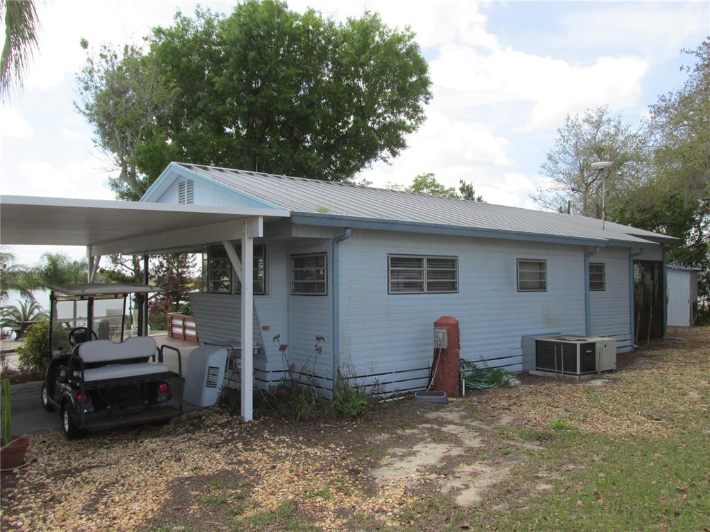 A light blue mobile home with a metal roof, carport, and golf cart parked outside — 7 BLUE QUILL CIRCLE, LAKE WALES, FL