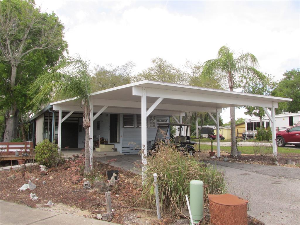 A single-story mobile home with a large white carport and a landscaped front yard — 7 BLUE QUILL CIRCLE, LAKE WALES, FL