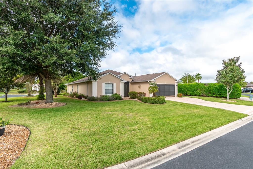 A single-story house with a tan exterior, a large front lawn, and a paved driveway — 15692 SW 11TH COURT ROAD, OCALA, FL