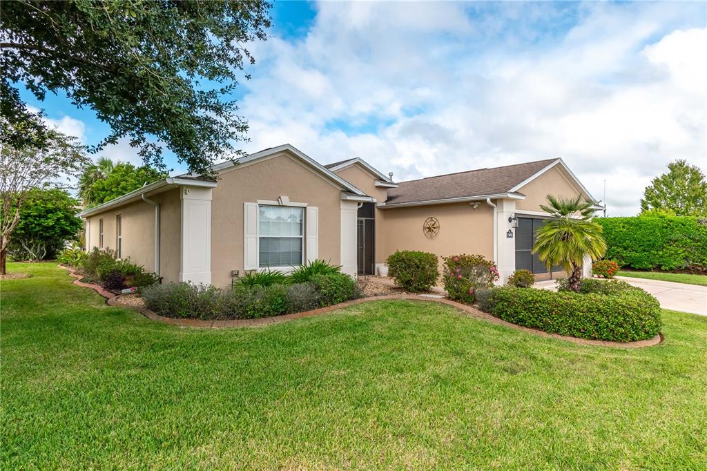 A single-story tan house with a front lawn, landscaping, and a two-car garage — 15692 SW 11TH COURT ROAD, OCALA, FL